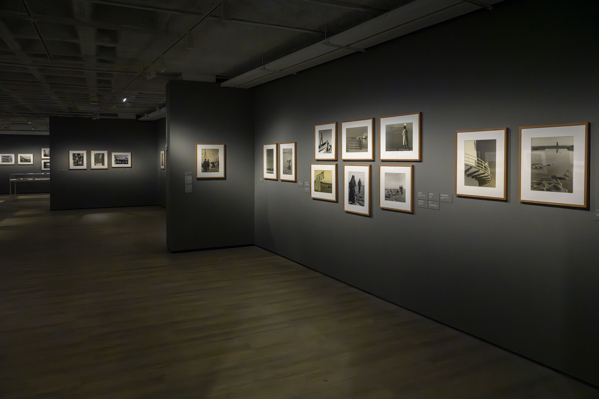 Fotografías enmarcadas en las paredes de una sala de la exposición, con una vista en profundidad del recorrido.