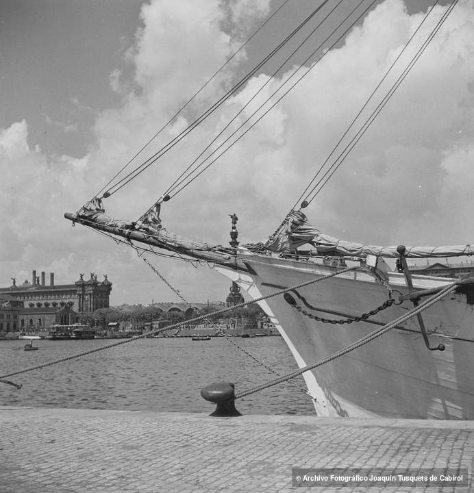 Bauprés de velero amarrado en el puerto de Barcelona, con vista al Mirador de Colón y al edificio de la Duana al fondo. Joaquín Tusquets de Cabirol, c. 1950.